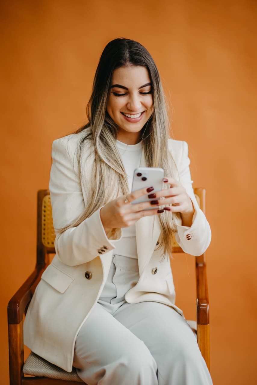 Patricia em foto descontraida com celular para atendimento via WhatsApp